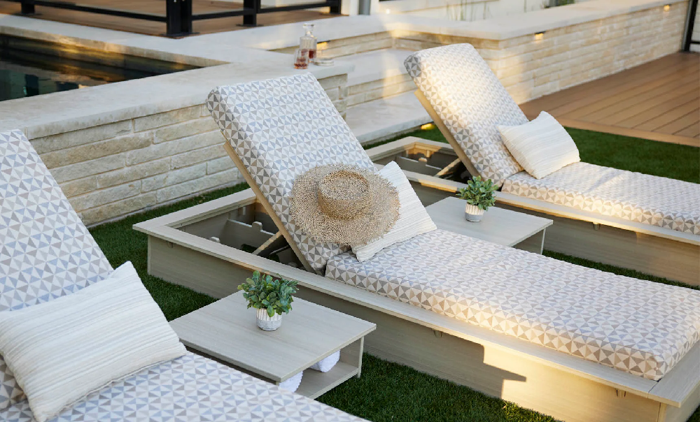Premium cushioned chaise lounges with integrated side tables creating a luxurious commercial poolside relaxation area.